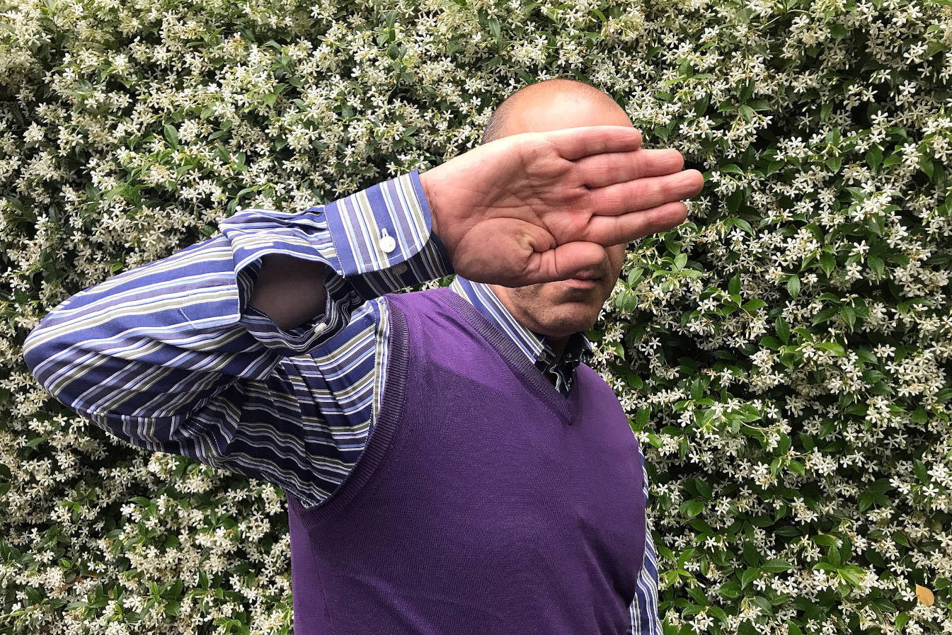 well dressed man holding hand up to cover his face