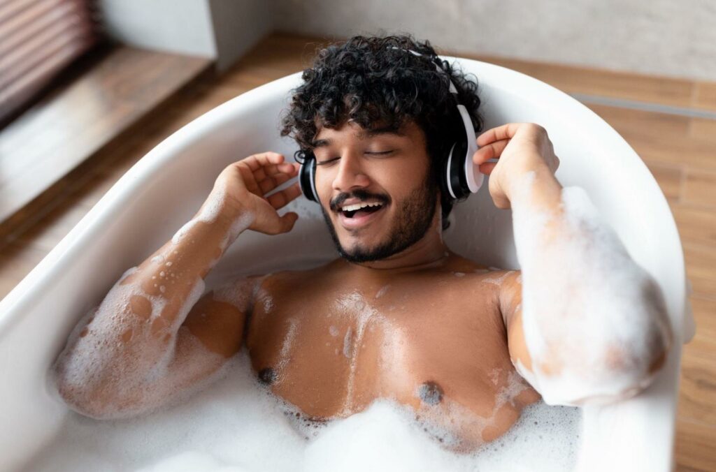 smiling man in bathtub with headphones