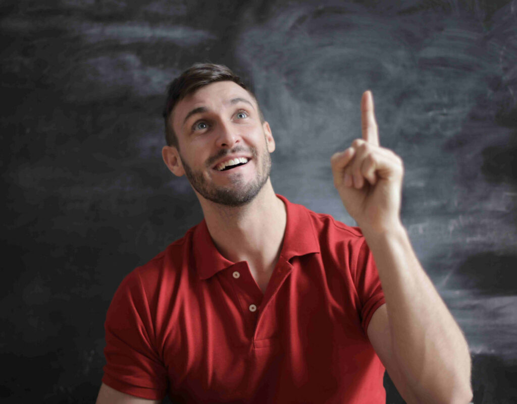 man in red shirt, smiling, pointing at ceiling