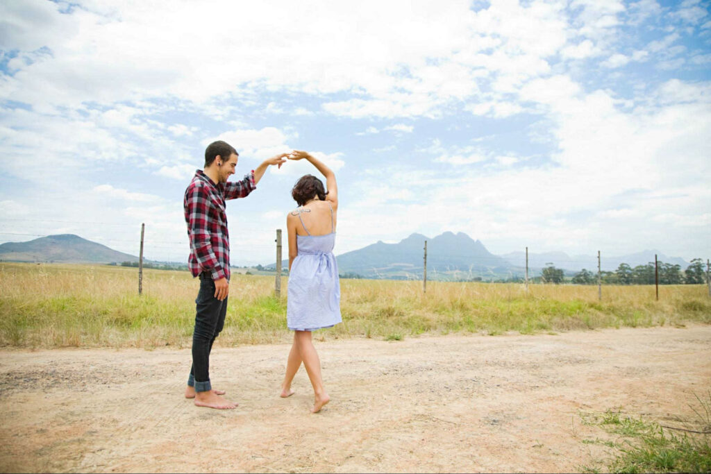 man spinning a woman in a dance on dirt road