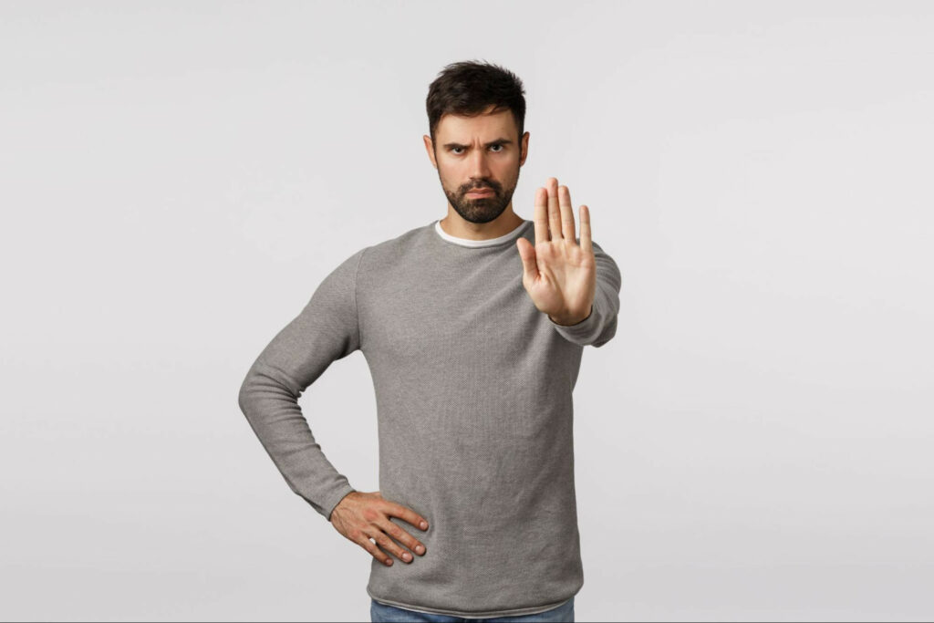 man with facial hair holding up hand to signal stop