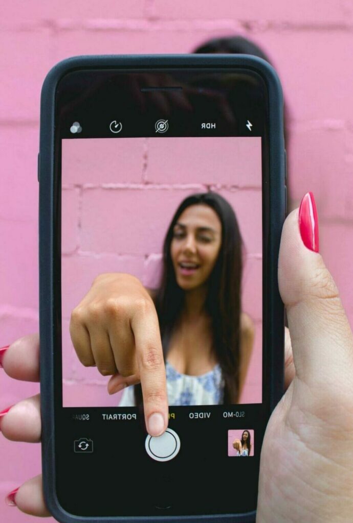 woman taking a photo of herself leaning through cell phone