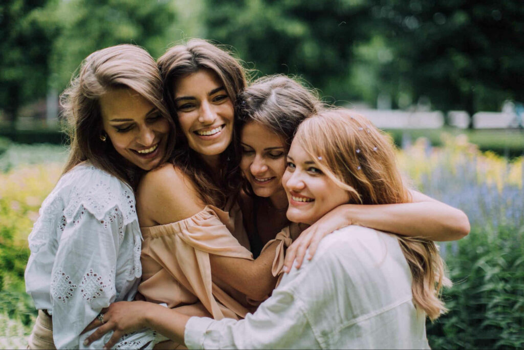 group of four women smiling and hugging