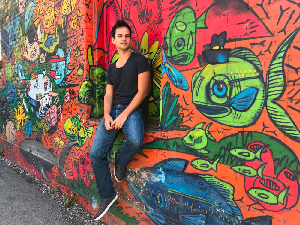 man posing in front of vibrant street art, distracting background