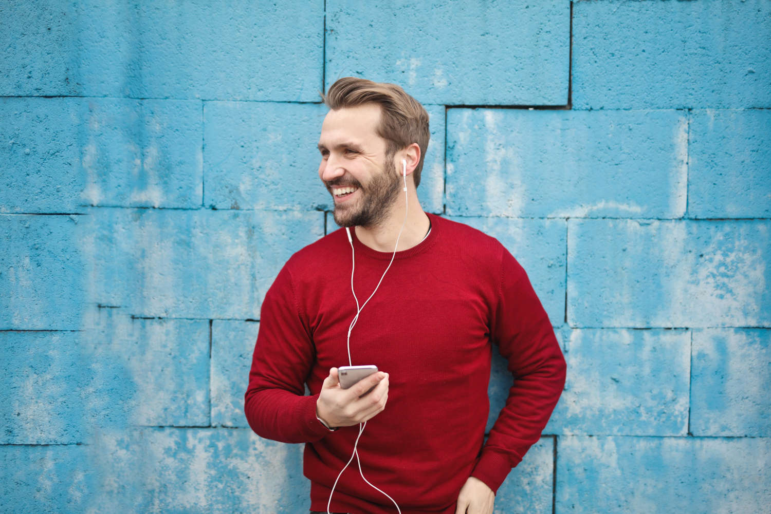 blonde man smiling, perfect profile photo, red sweater, blue background
