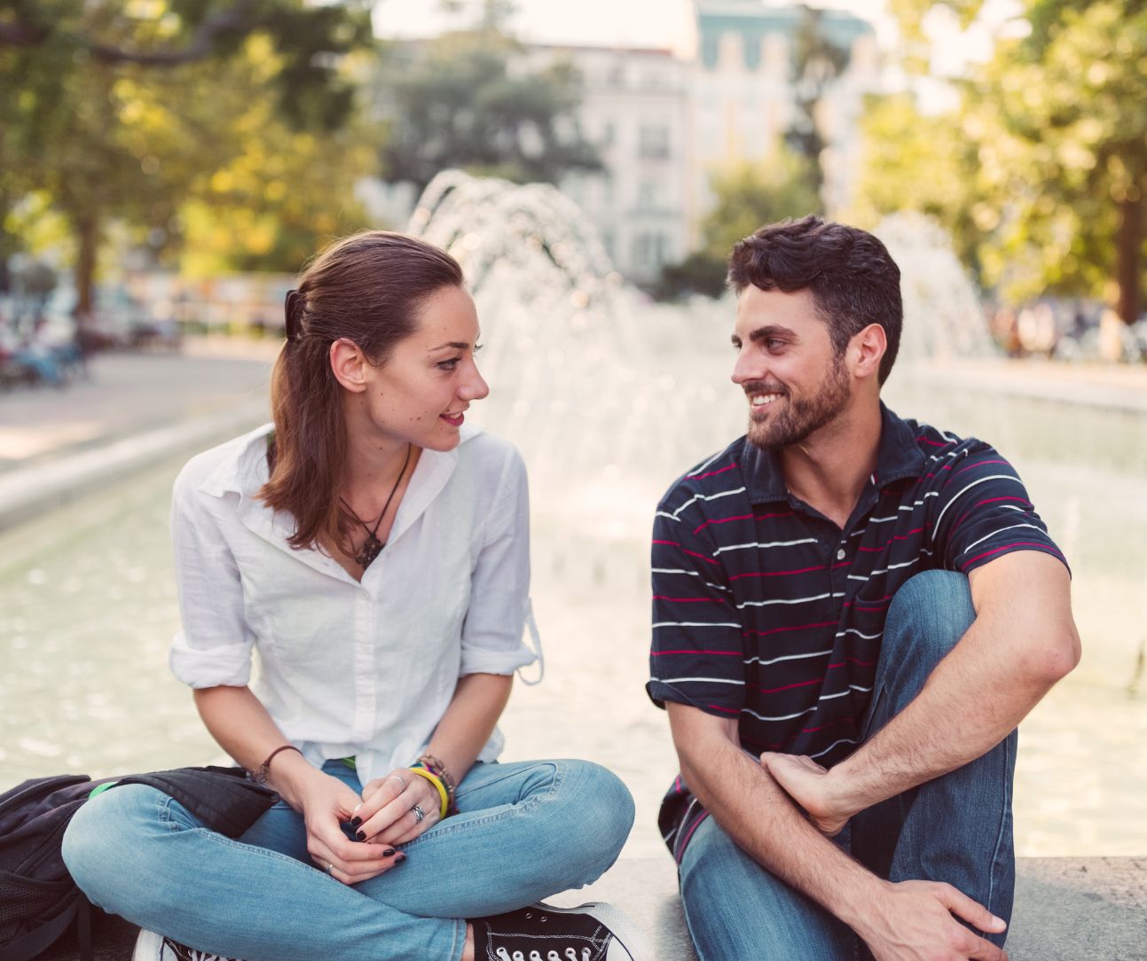 two people sitting by a fountain on date, discussing