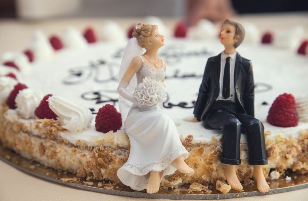 wedding cake toppers of bridge and groom sitting on the cake
