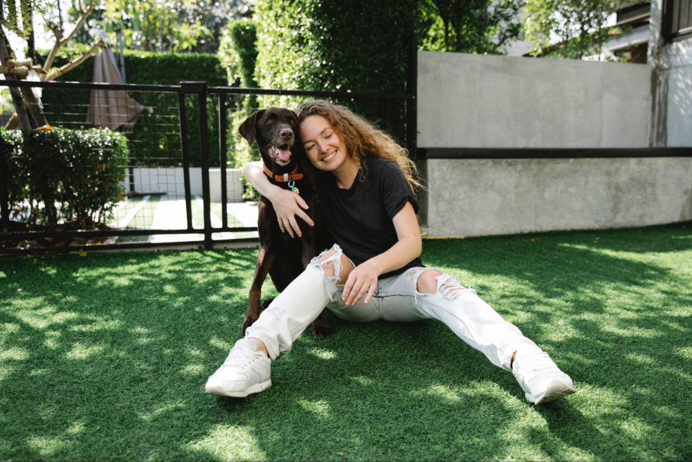 woman sitting on grass and hugging her dog, good full-body dating app profile example
