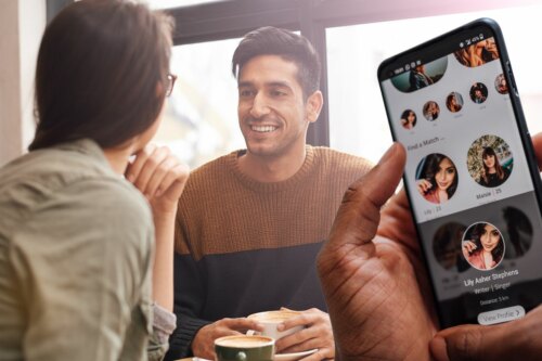 man and woman on cafe date with hand with phone on dating app