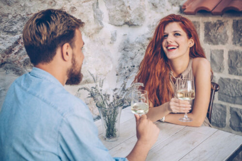 woman laughing with a man toasting with white wine