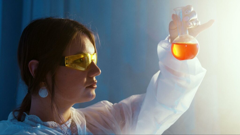 woman looking at a beaker, doing chemistry