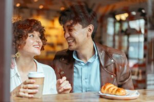 couple laughing together over a cup of coffee at a cafe