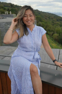 54 year old woman posing in a blue dress on a balcony, great example of a good dating app profile photo for singles over 50 years old