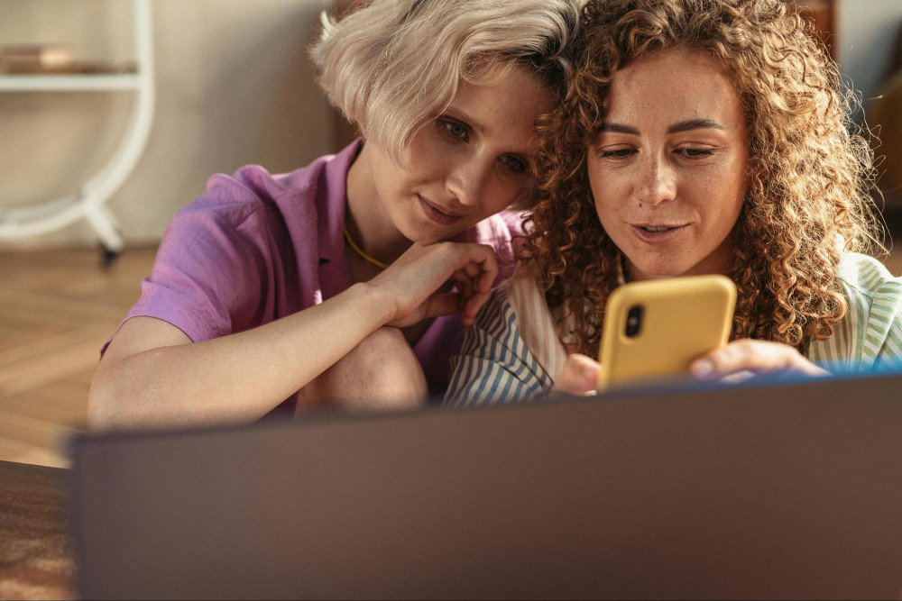 two women reading off their phone looking at dating profiles