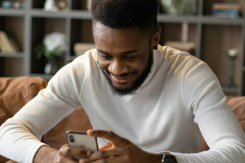 man looking at his phone smiling at his messages on dating apps