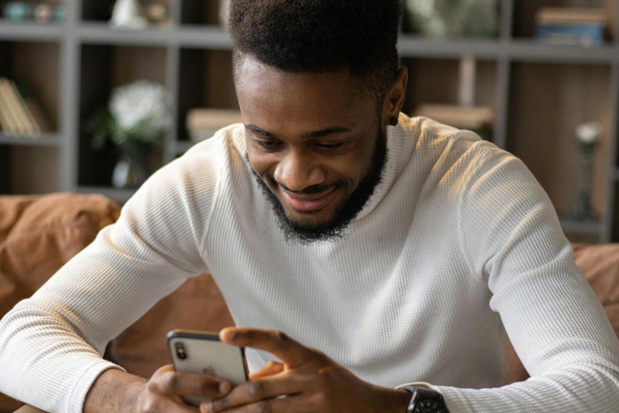 man looking at his phone smiling at his messages on dating apps