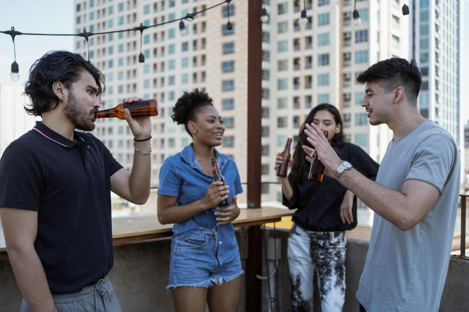 friends talking over drinks on balcony, city skyline
