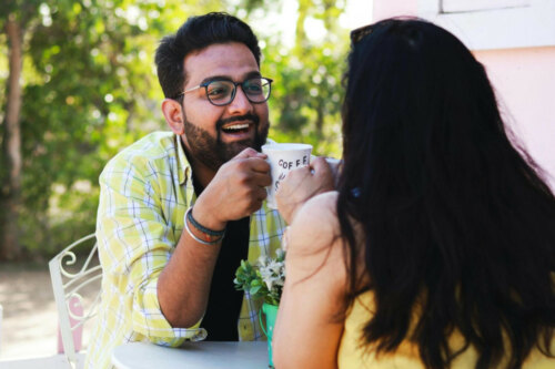 Single man and single woman on date, laughing over coffee in the cafe