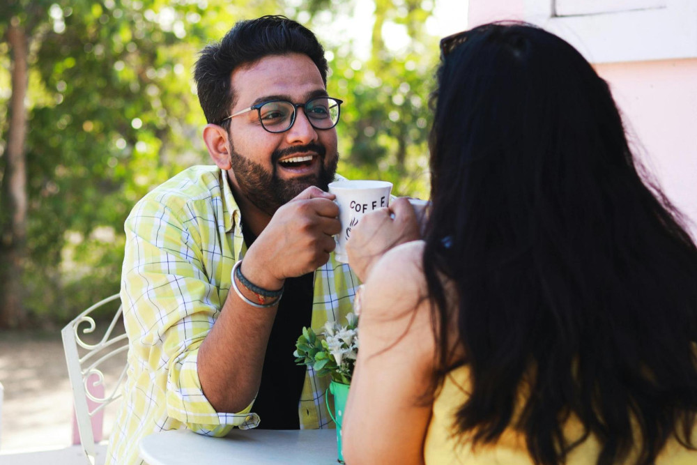 Single man and single woman on date, laughing over coffee in the cafe