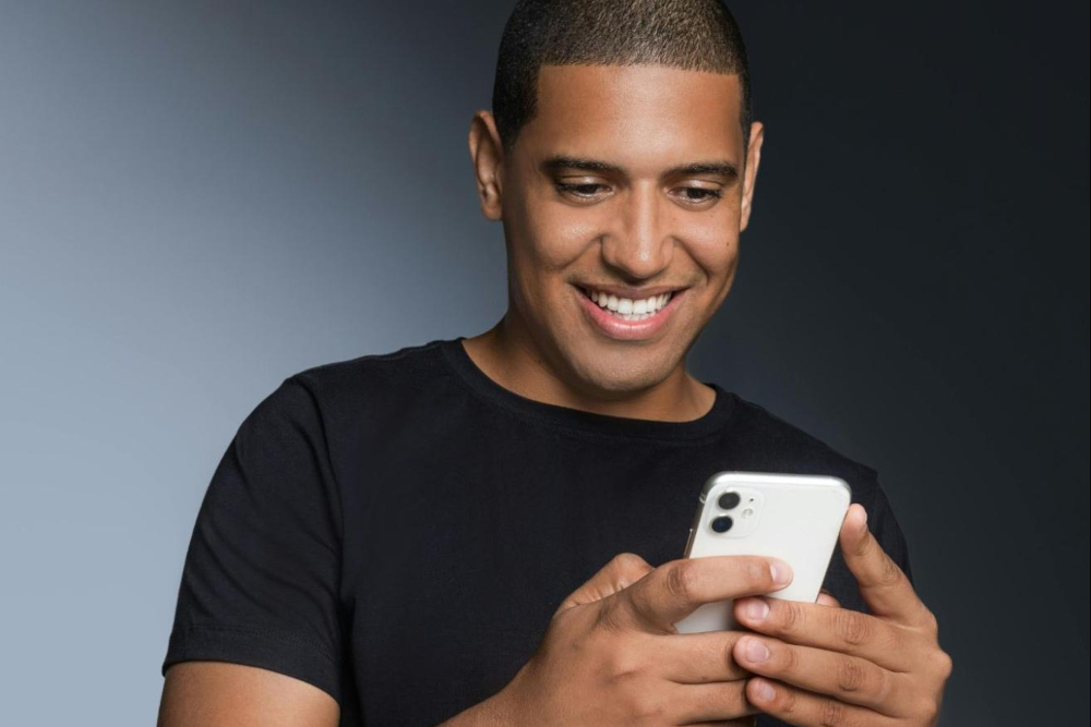man smiling at his cell phone as he's scrolling tinder