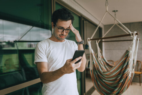 man looking at his phone confused